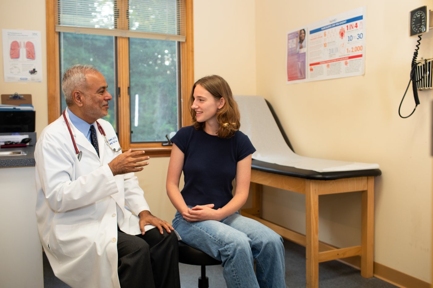 Dr. Anwar in his white coat with a patient